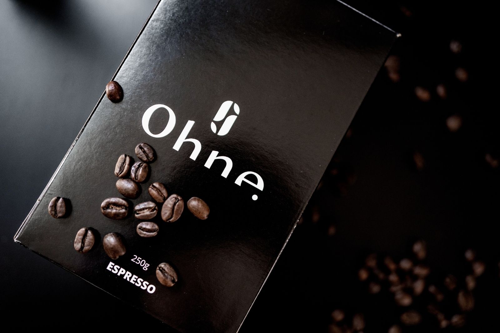 Entkoffeinierter Espresso von OHNE zusammen mit vielen Kaffeebohnen auf schwarzem Hintergrund