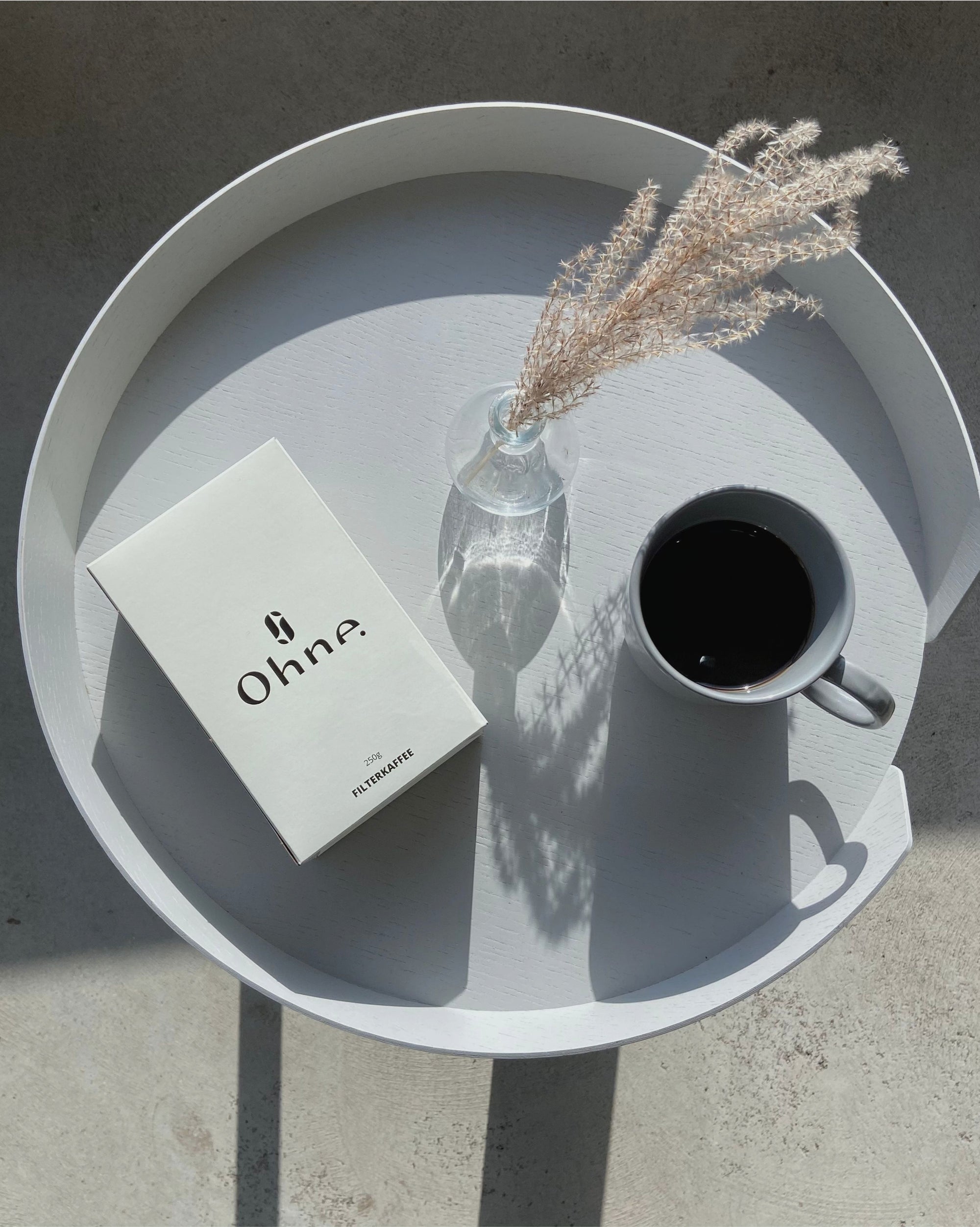 Entkoffeinierter Filterkaffee von OHNE steht auf einem Tisch neben einer Tasse Kaffee, welcher entkoffeiniert ist