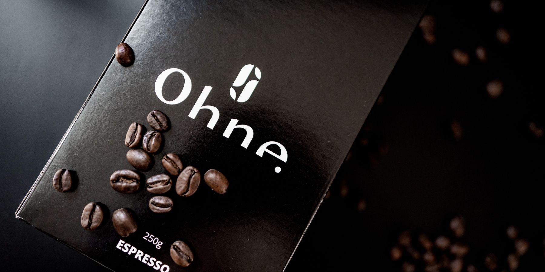 Entkoffeinierter Espresso von OHNE zusammen mit vielen Kaffeebohnen auf schwarzem Hintergrund mit weißer Schrift